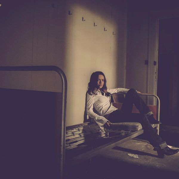 A person sitting cross-legged, meditating in a minimalist dark room with a single beam of light.